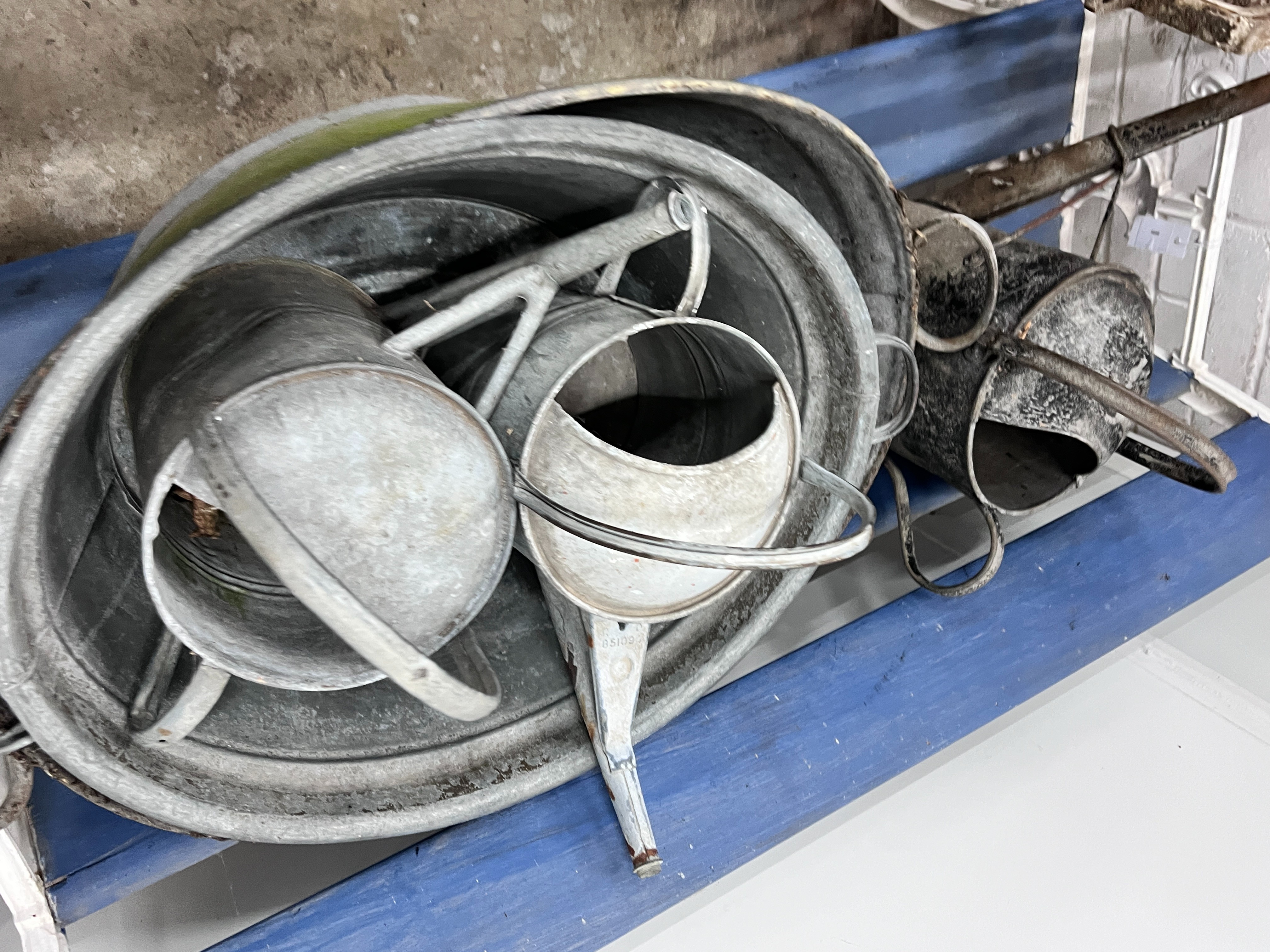 Ten assorted galvanised watering cans and containers, largest width 86cm